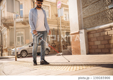 Blind man with white cane and sunglasses is in the city 139165900
