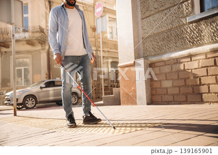 Walking on the pavement. A blind man with white cane is in the city 139165901