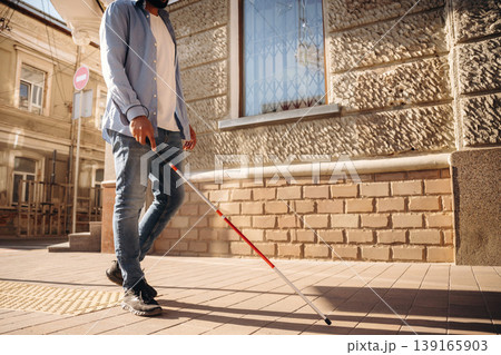 Walking on the pavement. A blind man with white cane is in the city 139165903