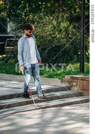 Blind man with white cane and sunglasses is in the city 139165915