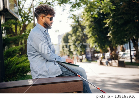 Special Braille technique for reading. Blind man with white cane and sunglasses is in the city Special Braille technique for reading. Blind man with white cane and sunglasses is in the city 139165916