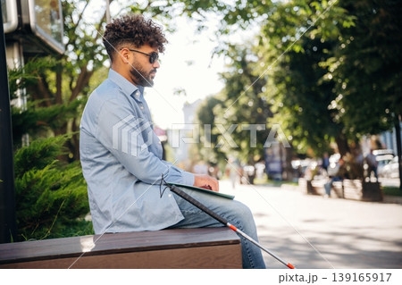Special Braille technique for reading. Blind man with white cane and sunglasses is in the city 139165917