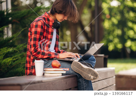 Education conception, with laptop. Male student is in the public park outdoors Education conception, with laptop. Male student is in the public park outdoors 139166117