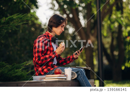 Time for lunch, with food. Male student is in the public park outdoors Time for lunch, with food. Male student is in the public park outdoors 139166141