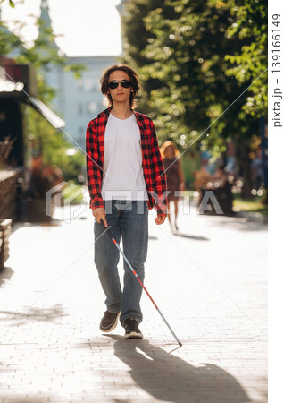 Front view, walking. Blind young guy is in the town outdoors 139166149