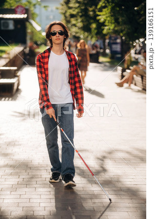 Front view, walking. Blind young guy is in the town outdoors 139166151