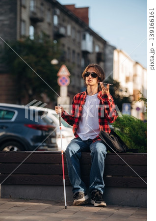 Smartphone in hand, talking. Blind young guy is in the town outdoors 139166161
