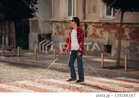 View from the side, walking. Blind young guy is in the town outdoors 139166167
