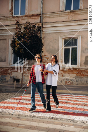 Woman is helping blind guy cross the road Woman is helping blind guy cross the road 139166178