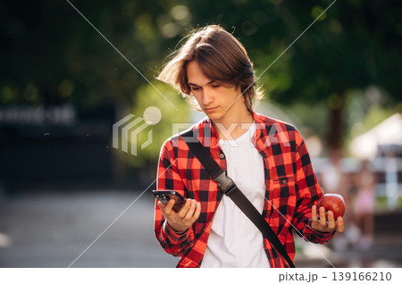 At sunny daytime. Young student is having a walk in the town At sunny daytime. Young student is having a walk in the town 139166210