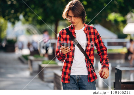At sunny daytime. Young student is having a walk in the town At sunny daytime. Young student is having a walk in the town 139166212