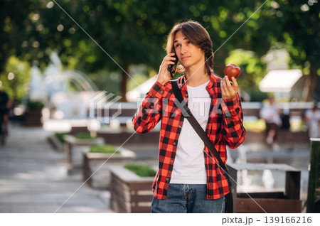 In red checkered shirt. Young student is having a walk in the town 139166216