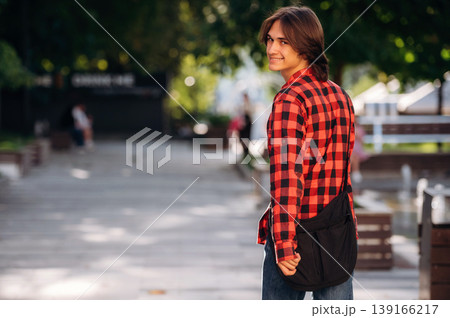 In red checkered shirt. Young student is having a walk in the town 139166217