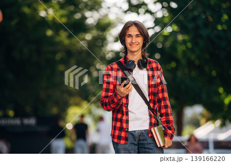 Wireless headphones on the neck. Young student is having a walk in the town Wireless headphones on the neck. Young student is having a walk in the town 139166220