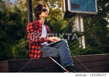 Technique of Braille reading. Blind young guy is in the town outdoors 139166275