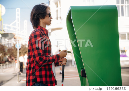 By the ATM, using credit card. Blind young guy is in the town outdoors 139166288