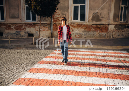 Crossing the road. Blind young guy is in the town outdoors 139166294