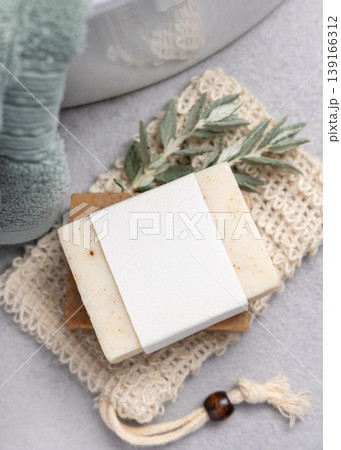 Beige solid soap bar with blank paper label mockup near with leaves and light green bath towel Beige solid soap bar with blank paper label mockup near with leaves and light green bath towel 139166312
