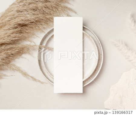 Blank vertical card mockup near pampas grass and beige stone top view, boho wedding stationery 139166317