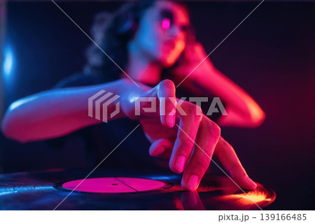 Vinyl record manipulation by DJ. Guy is indoors at night with neon lighting 139166485