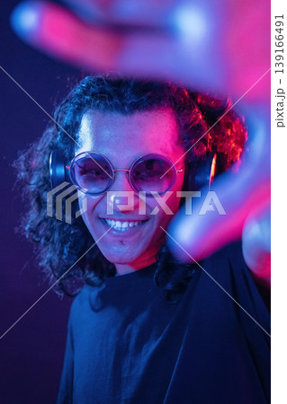 Performance of DJ, in headphones. Guy is indoors at night with neon lighting Performance of DJ, in headphones. Guy is indoors at night with neon lighting 139166491