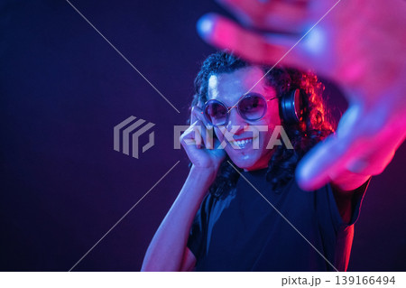 Performance of DJ, in headphones. Guy is indoors at night with neon lighting 139166494