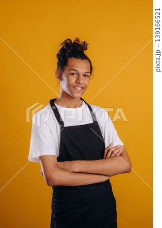 Barista is in apron. Young guy is against yellow background Barista is in apron. Young guy is against yellow background 139166521