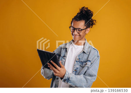 Digital tablet is in hands. Young guy is against yellow background 139166530