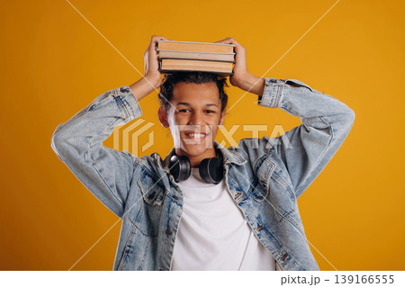 Ready to learn, with books. Young guy is against yellow background 139166555