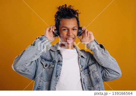 In jean jacket. Young guy is against yellow background In jean jacket. Young guy is against yellow background 139166564