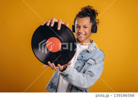 Retro vinyl record in hands. Young guy is against yellow background 139166566