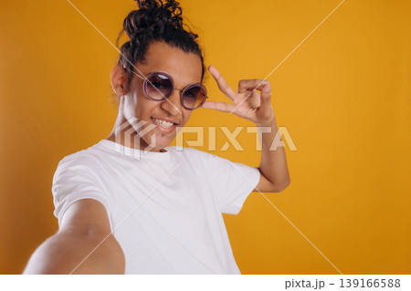 Selfie time, posing. Young guy is against yellow background Selfie time, posing. Young guy is against yellow background 139166588