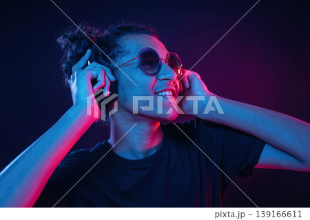 Listening to the music in headphones. Guy is indoors at night with neon lighting 139166611