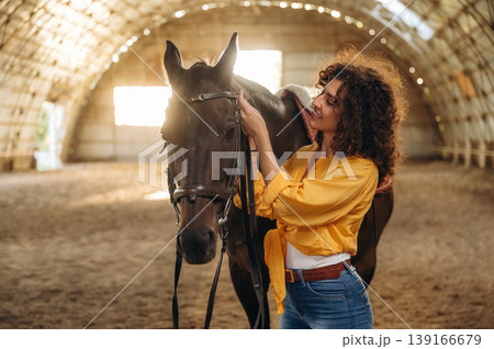 Feeling good, taking care of animal. Beautiful young woman is with horse in hangar 139166679