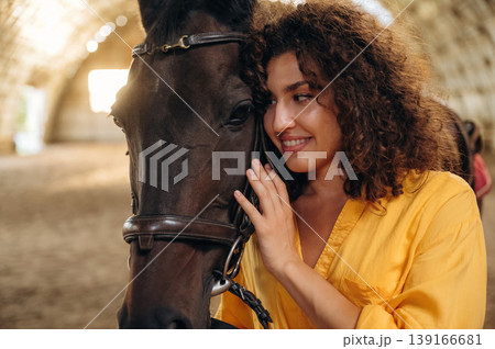 Feeling good, taking care of animal. Beautiful young woman is with horse in hangar 139166681