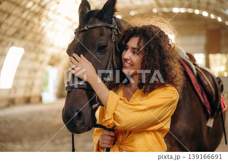 Smiling, having fun. Beautiful young woman is with horse in hangar Smiling, having fun. Beautiful young woman is with horse in hangar 139166691