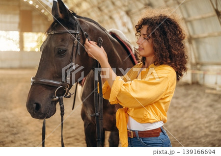 Taking care of animal. Beautiful young woman is with horse in hangar 139166694