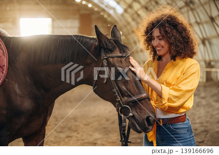 Taking care of animal. Beautiful young woman is with horse in hangar Taking care of animal. Beautiful young woman is with horse in hangar 139166696