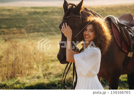 Woman in white dress is with horse on the countryside field 139166765