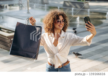Selfie time. Happy woman is with shopping bags in town Selfie time. Happy woman is with shopping bags in town 139166816