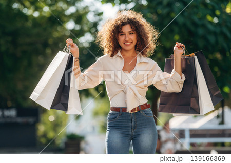 Already bought the quality product. Happy woman is with shopping bags in town Already bought the quality product. Happy woman is with shopping bags in town 139166869