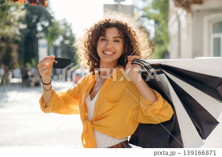 Credit card is in hand. Happy woman is with shopping bags in town 139166871