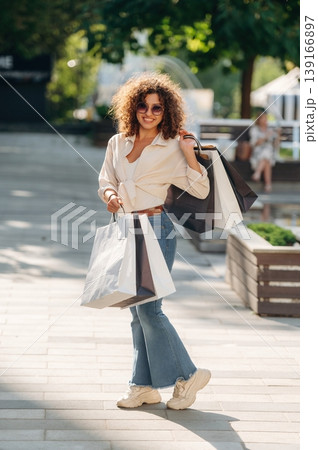 Model is standing and posing. Happy woman is with shopping bags in town Model is standing and posing. Happy woman is with shopping bags in town 139166897