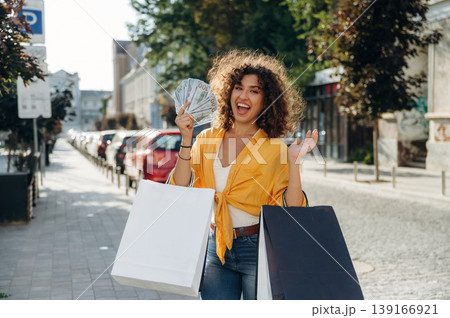 Money to spend. Happy woman is with shopping bags in town Money to spend. Happy woman is with shopping bags in town 139166921