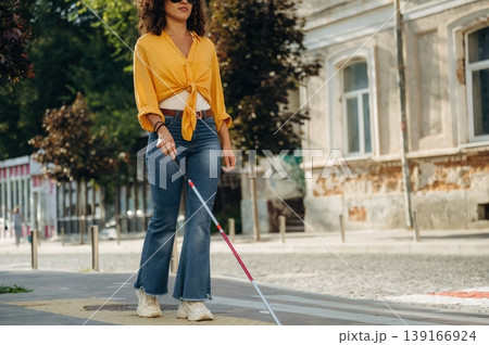 Having a walk, using white cane. A blind woman is in the modern city at daytime 139166924