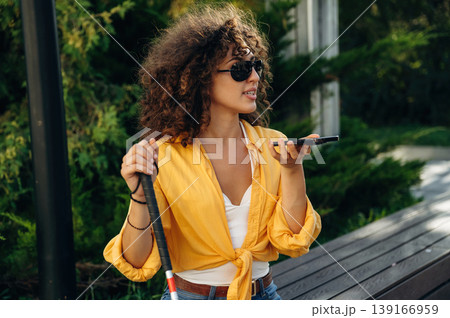 Talking by phone. A blind woman is in the modern city at daytime 139166959