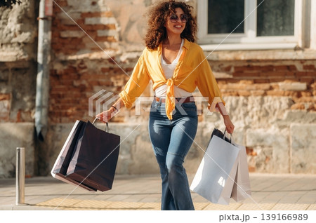 Crossing the road. Happy woman is with shopping bags in town Crossing the road. Happy woman is with shopping bags in town 139166989