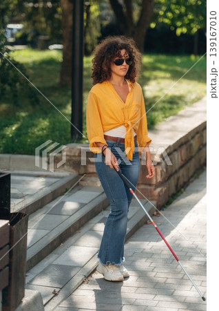By the help of white cane. A blind woman is in the modern city at daytime By the help of white cane. A blind woman is in the modern city at daytime 139167010