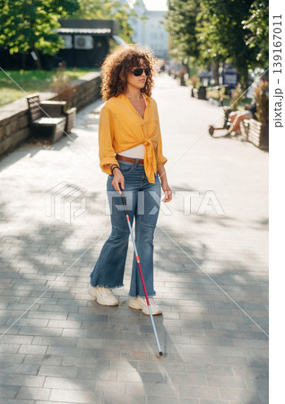 By the help of white cane. A blind woman is in the modern city at daytime By the help of white cane. A blind woman is in the modern city at daytime 139167011
