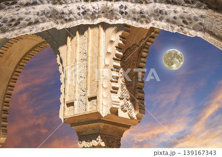 Arches in Islamic (Moorish) style (against the sunset with the super moon) in Alhambra, Granada, Spain  139167343
